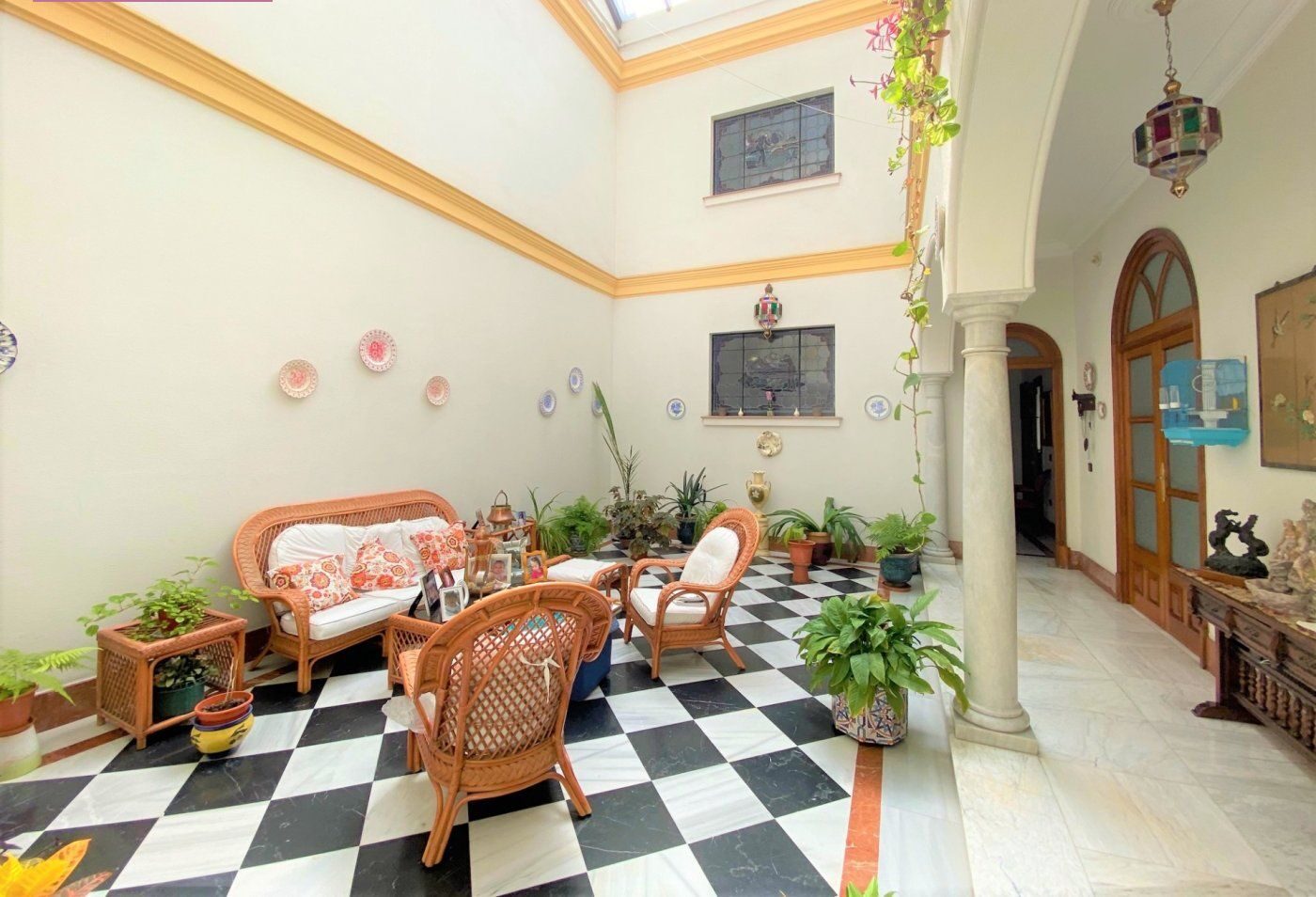 A wider three-quarter view of the patio with column, gallery arch and the arched door opposite.